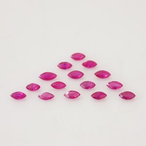 Può includere: Un gruppo di 17 pietre preziose di rubino di forma marquise disposte a forma di triangolo su uno sfondo bianco.