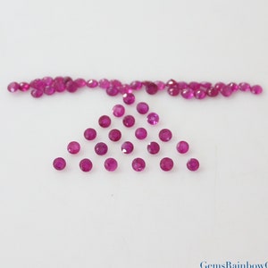 Könnte beinhalten: Eine Sammlung von 30 runden, rosafarbenen Rubingesteinen. Die Edelsteine sind in einer dreieckigen Form angeordnet, mit einer Reihe von Edelsteinen an der Spitze.