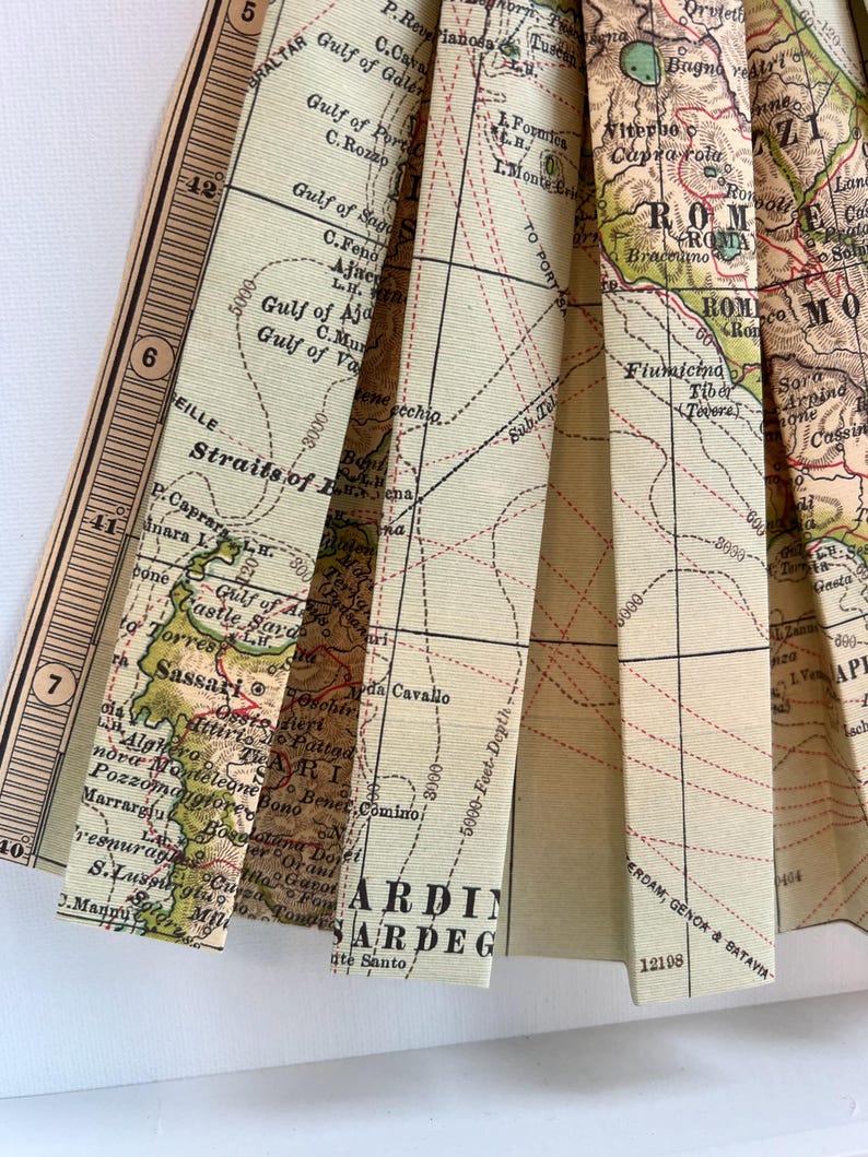 Puede incluir: Un mapa vintage de Italia y Cerde&ntilde;a, doblado en forma de abanico. El mapa est&aacute; impreso en papel color crema con l&iacute;neas y texto marrones y rojos. El mapa muestra las ciudades de Roma, Florencia y N&aacute;poles, as&iacute; como la isla de Cerde&ntilde;a.
