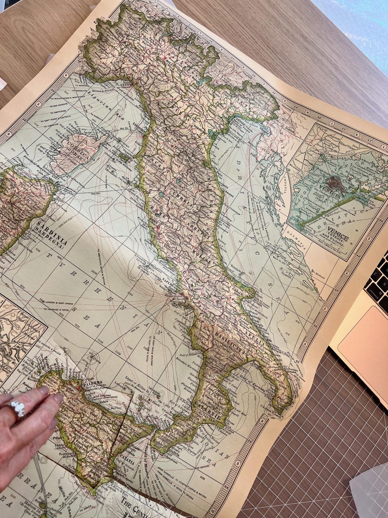 Puede incluir: Un mapa vintage de Italia con marcas detalladas de ciudades, pueblos y caracter&iacute;sticas geogr&aacute;ficas. El mapa est&aacute; impreso en papel de color crema con acentos marrones y verdes. El mapa est&aacute; ligeramente curvado en los bordes.