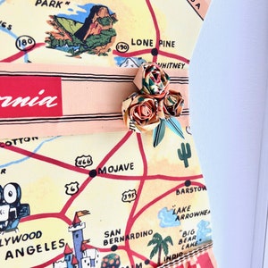 Pu&ograve; includere: Un'opera d'arte unica con una mappa vintage della California, con un abbellimento floreale decorativo. La mappa include punti di riferimento come Disneyland e Hollywood. Il pezzo ha un bordo a balze ed &egrave; incorniciato.