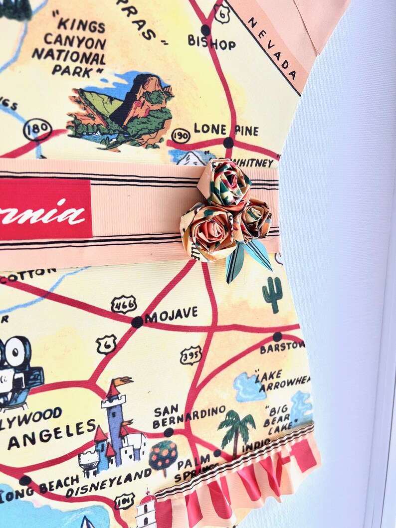 Pu&ograve; includere: Un'opera d'arte unica con una mappa vintage della California, con un abbellimento floreale decorativo. La mappa include punti di riferimento come Disneyland e Hollywood. Il pezzo ha un bordo a balze ed &egrave; incorniciato.