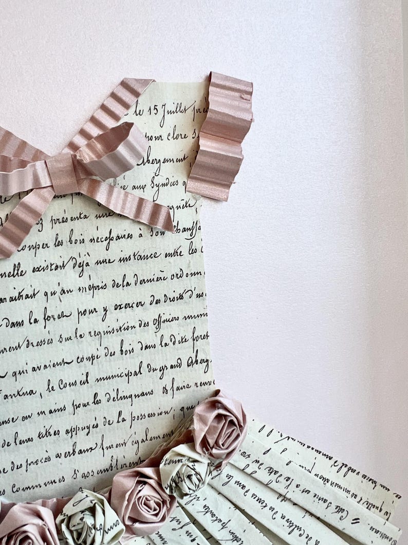 May include: A vintage letter with handwritten text in French, partially covered by a pink ribbon and paper roses. The text reads "le 15 Juilles fra rom clore s thegament Syndies of quite onper les bois r&eacute;cepaines &agrave; son hauffe nelle existait de deja mue instance mtre les i araitrait qu'an m&eacute;pris dela derni&egrave;re ordonn. Dans la force pour y exercer &theta;&alpha; &delta;&iota;ό&nu;&omicron; &delta;'&omicron;. rent dress&eacute;s sum le requisition des Officiers qui avaient coup&eacute; des bois dans la dite foret Fantua, le Conseil municipal dugrand Abay. anse on in aiss proue les d&eacute;lingnans faire de levas tithes appuy&eacute;s de la possession; que e des proc&eacute;s a erbans monregalement as Communes S'gos unbleness of renve"