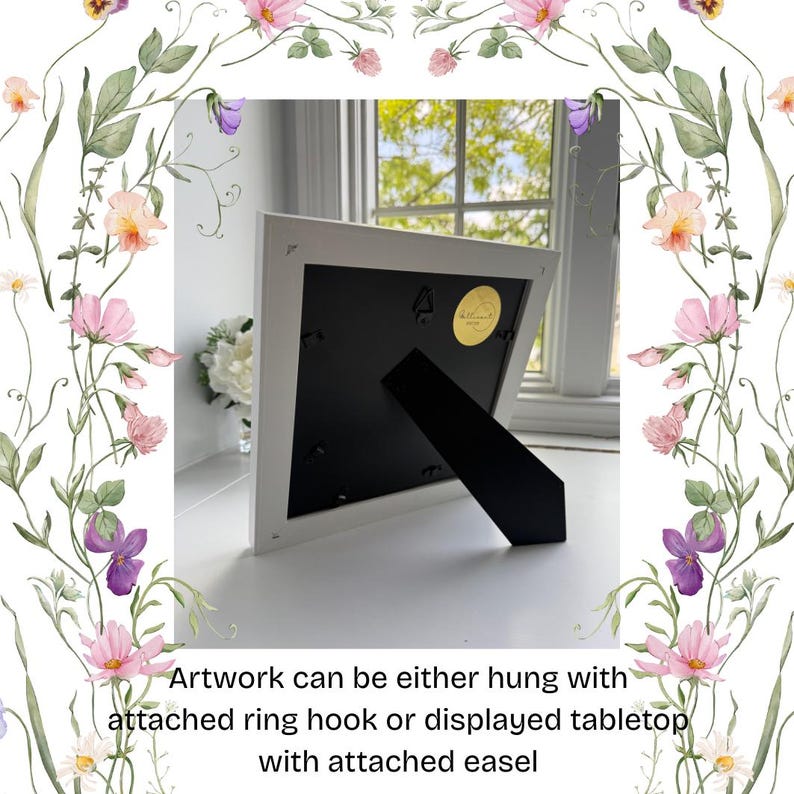 Pu&ograve; includere: Opera d'arte con cornice bianca con retro nero e cavalletto. Testo: L'opera d'arte pu&ograve; essere appesa con un gancio ad anello o esposta sul tavolo con un cavalletto. Bordo floreale con fiori rosa, viola e gialli.