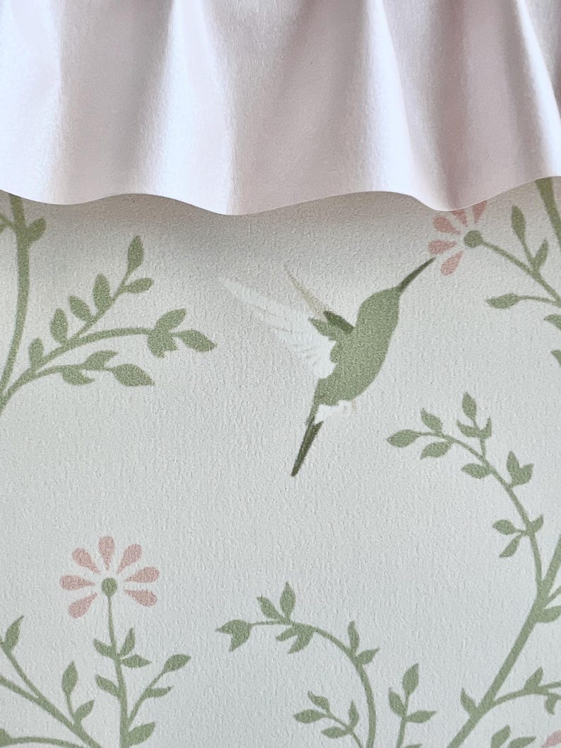 May include: A white background with a green hummingbird and pink flowers. The background has a subtle texture.