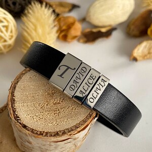 Puede incluir: Pulsera de cuero negro con abalorios de metal plateado grabados con los nombres "T", "David", "Alice" y "Olivia".
