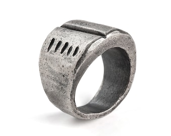 May include: A silver ring with a textured surface and a series of small indentations on the top.