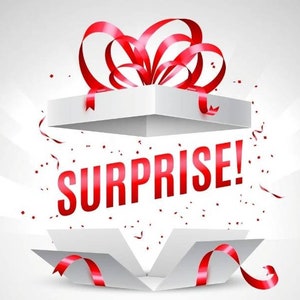 May include: A white gift box with a red ribbon and bow is open, revealing the word "SURPRISE!" in red letters. Confetti is scattered around the box.