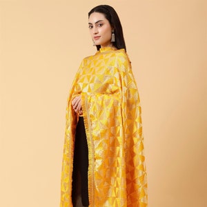 Könnte beinhalten: Ein gelber bestickter Dupatta mit geometrischem Muster. Der Dupatta hat einen Fransenrand und einen Quaste.