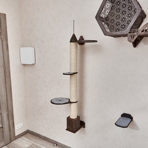 May include: A brown wooden cat tree with a scratching post and multiple platforms. The cat tree is mounted on a white wall. There are also several other cat shelves on the wall.