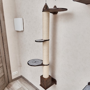 May include: A beige cat tree with a brown wooden base and three platforms. The cat tree is mounted on a white wall.
