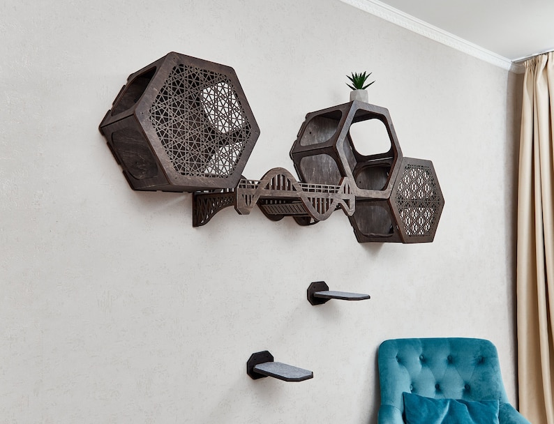 Puede incluir: Un &aacute;rbol para gatos de madera marr&oacute;n oscuro con un dise&ntilde;o hexagonal. El &aacute;rbol para gatos tiene varios niveles y una peque&ntilde;a planta en la parte superior. El &aacute;rbol para gatos est&aacute; montado en una pared blanca.