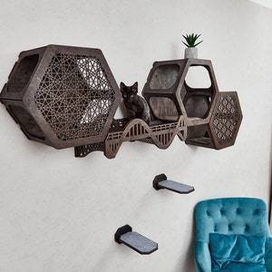 Puede incluir: Un &aacute;rbol para gatos de madera con m&uacute;ltiples niveles y un dise&ntilde;o hexagonal. El &aacute;rbol para gatos est&aacute; montado en una pared y tiene un gato negro sentado en uno de los niveles. El &aacute;rbol para gatos est&aacute; hecho de madera oscura y tiene un patr&oacute;n geom&eacute;trico.