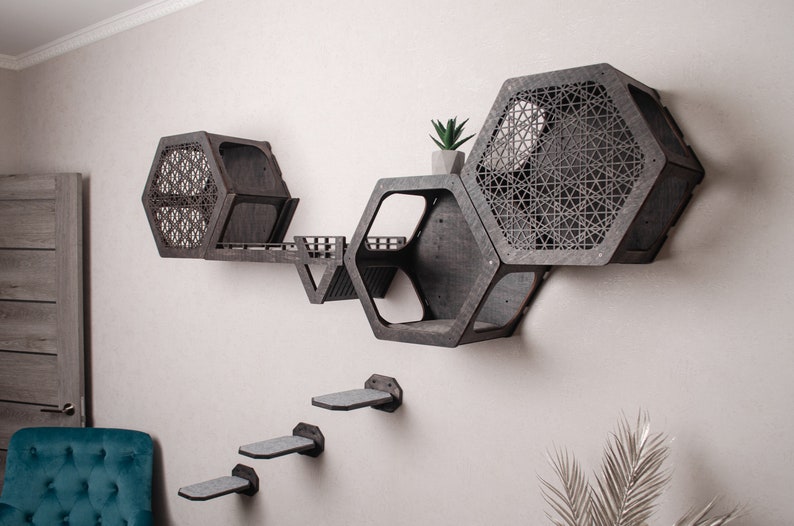 Puede incluir: Un &aacute;rbol para gatos de pared hecho de madera oscura con estantes hexagonales y una rampa de escalada. Los estantes tienen recortes geom&eacute;tricos y la rampa est&aacute; hecha de madera m&aacute;s clara. Hay tres peque&ntilde;as plataformas unidas a la pared debajo de la estructura principal.