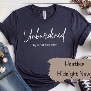 May include: A navy blue t-shirt with the text "Unburdened by what has been" in white lettering. The shirt is made of a soft, comfortable material and is available in Heather Midnight Navy.