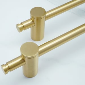 Pode incluir: Duas puxadores de armário de metal dourado com um design cilíndrico. Os puxadores têm um acabamento liso e escovado.