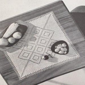 May include: A white crocheted doily with a square pattern sits on a wooden table with a bowl of fruit and a small bowl of nuts.