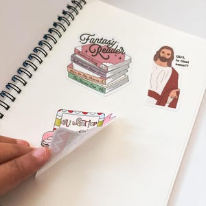 a person is holding a book with stickers on it