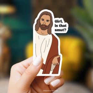 May include: A sticker featuring a cartoon illustration of Jesus with a beard and long hair, wearing a red and white robe. The text "Girl, is that smut?" is written in black text above Jesus's head.