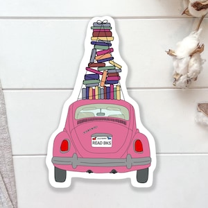 May include: A pink car sticker with a stack of colorful books on top. The car has a California license plate that reads "READ BKS". The sticker is on a white background.
