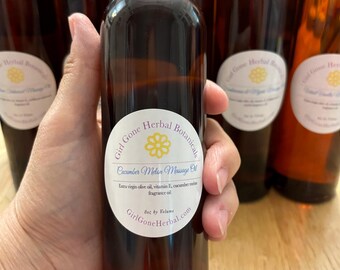 May include: A brown glass bottle with a black cap and a white label that reads "Girl Gone Herbal Botanicals Cucumber Melon Massage Oil Extra virgin olive oil, vitamin E, cucumber melon fragrance oil Bot by Volume GirlGoneHerbal.com"