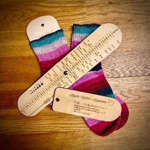 May include: A wooden sock knitting gauge with a ruler and a chart for different sock sizes. The gauge is labeled "Pocket Sockenincal 4-in-1" and "Handmade in Deutschland".