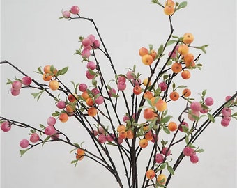 May include: A bouquet of artificial berry branches with pink and orange berries. The branches are brown and have green leaves.