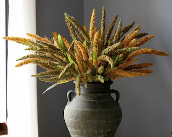May include: A large, rustic, green ceramic vase filled with a bouquet of dried, golden wheat-like flowers.