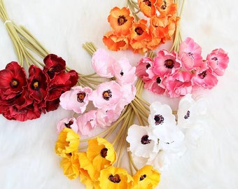 May include: A bouquet of artificial poppy flowers in various colors, including red, pink, white, and yellow. The flowers are arranged in a cluster and have a realistic appearance.