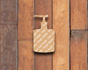 May include: A tan acrylic blank in the shape of a soap dispenser, with the words "Acrylic Blanks" and "Clear Cast Acrylic" printed on it. The blank is set against a backdrop of vertical wooden planks.