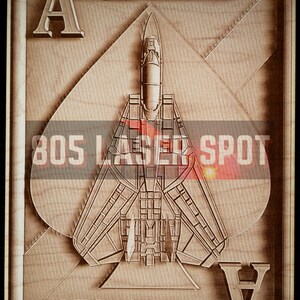 May include: A wooden plaque with a carved image of a fighter jet in the shape of a spade playing card. The text "BLACK ACES" is above the jet and below the jet. The text "805 LASER SPOT" is in the center of the image.