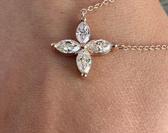 May include: A rose gold necklace featuring a pendant composed of four marquise-cut clear stones arranged in a flower-like shape. The delicate chain connects to the top and side of the central stone cluster, creating a refined and symmetrical jewelry piece.