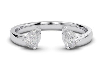 May include: A silver-toned open ring featuring two pear-shaped clear stones set at each end of the band. The band has a smooth, polished finish, and the stones are secured with small metal prongs, creating a gap between the two focal points.