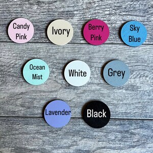 Puede incluir: Nueve discos redondos de madera de diferentes colores y con texto. Los colores son marfil, rosa caramelo, rosa baya, azul cielo, neblina oce&aacute;nica, blanco, gris, lavanda y negro. El texto en los discos dice: Marfil, Rosa caramelo, Rosa baya, Azul cielo, Neblina oce&aacute;nica, Blanco, Gris, Lavanda y Negro.