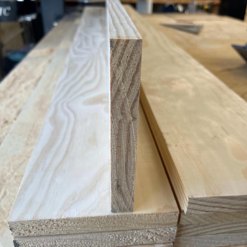 May include: Close-up of the edge of a wooden plank, showing the layers of wood that make up the plank. The wood is light brown in colour and has a smooth finish.
