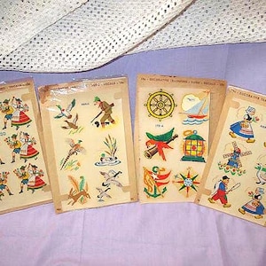 May include: Four vintage decorative transfer sheets with colorful illustrations. The sheets feature various themes, including folk dancers, nautical elements, hunting scenes, and Dutch figures. The transfers are on aged paper.