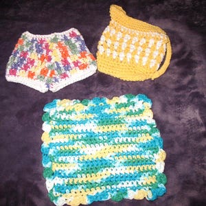 May include: Three crocheted items: a pair of colorful shorts, a yellow and white crocheted hat, and a green, blue, and white crocheted dishcloth.
