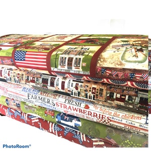 May include: Four pieces of fabric with a patriotic theme. The top fabric features a red, white, and blue American flag, a red brick building, and a sign that says "General Store". The second fabric features a red, white, and blue American flag, a sign that says "Bleached", and a sign that says "Welcome Brand". The third fabric features a sign that says "Farmers Fresh Strawberries", a sign that says "Roller Mills", and a sign that says "Bread Cake Biscuit". The fourth fabric features a sign that says "10 LBS. NET", a sign that says "General Store", and a sign that says "Complete the Chickens".