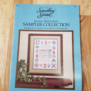 May include: A sampler cross stitch pattern booklet featuring a colourful cross stitch design on the cover. The design includes a quote that reads "No matter what, no matter where, it's always home if love is there." The design also features a variety of colourful flowers, birds, and houses.