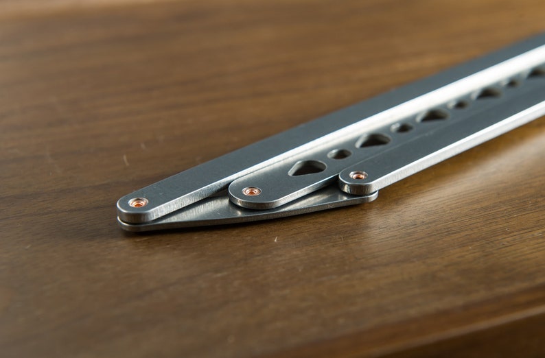 May include: A silver folding knife with a textured handle and copper-colored rivets. The knife is partially open, revealing the blade.