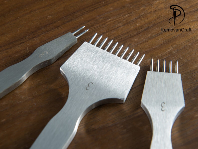 May include: Three stainless steel leather working tools with multiple prongs, each with a handle and the number "3" etched on the surface. The tools are arranged on a wooden surface. The logo "KemovanCraft" is in the upper right corner.