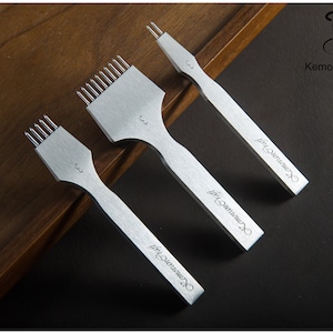 May include: Three silver leathercraft tools with multiple prongs, arranged on a dark surface. The tools have a handle and a numbered marking. The text "KemovanCraft" is printed on the handle of each tool.