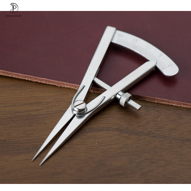 May include: A silver leather measuring tool with a graduated scale. The tool is used to measure the thickness of leather.