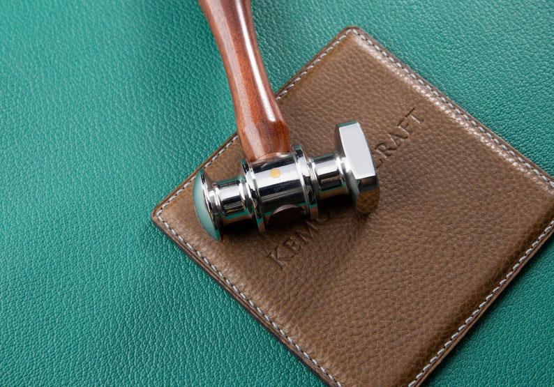 May include: A silver and wooden hammer with a textured brown leather surface with the word "KRAFT" embossed on it.