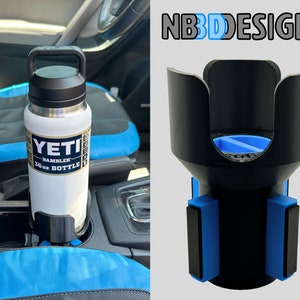 May include: A black 3D printed car cup holder with blue magnetic bases. The holder is designed to fit a Yeti Rambler 36 oz bottle. The text "NBDESIGNS" is printed in white on a black background.