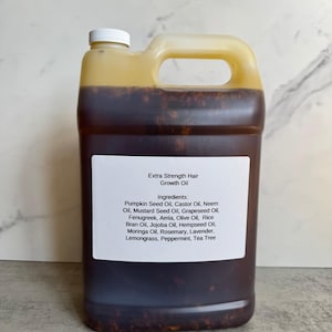 May include: A large, translucent plastic jug filled with a dark brown liquid containing visible herbal particles. The white label reads: Extra Strength Hair Growth Oil, Ingredients: Pumpkin Seed Oil, Castor Oil, Neem Oil, Mustard Seed Oil, Grapeseed Oil, Fenugreek, Amla, Olive Oil, Rice Bran Oil, Jojoba Oil, Hempseed Oil, Moringa Oil, Rosemary, Lavender, Lemongrass, Peppermint, Tea Tree.