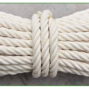 May include: A close-up of a thick, white cotton rope coiled together. The rope is tightly wound and has a smooth, natural texture.
