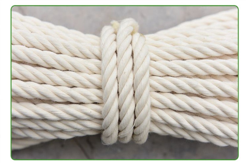May include: A close-up of a thick, white cotton rope coiled together. The rope is tightly wound and has a smooth, natural texture.
