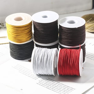 May include: Six spools of elastic cord in various colors, including yellow, brown, black, white, and red. The spools are arranged in two rows of three.
