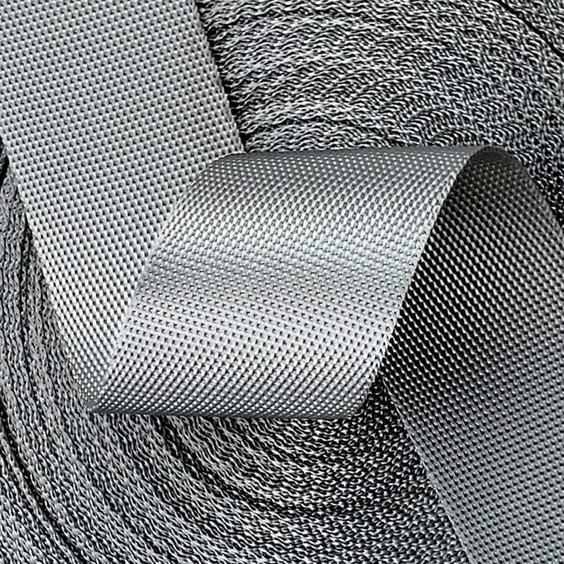 May include: Close-up of a roll of silver gray webbing with a textured surface.